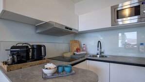 Una cocina moderna con microondas integrado, cafetera y tabla de cortar de madera.