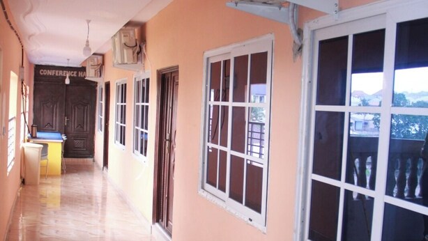 A corridor with a marble floor, a conference hall door, and windows with blinds. - Spacious Comfort Stay  at Asabi - Kumasi (Kumasi)