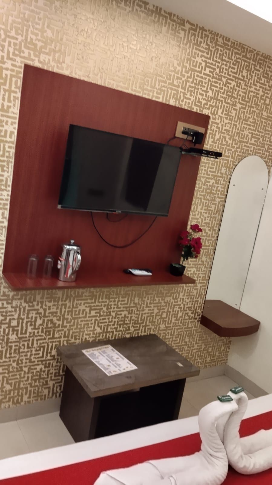 Une chambre dotée d’un téléviseur fixé au mur, d’une petite machine à café, d’une télécommande et d’un cygne décoratif.