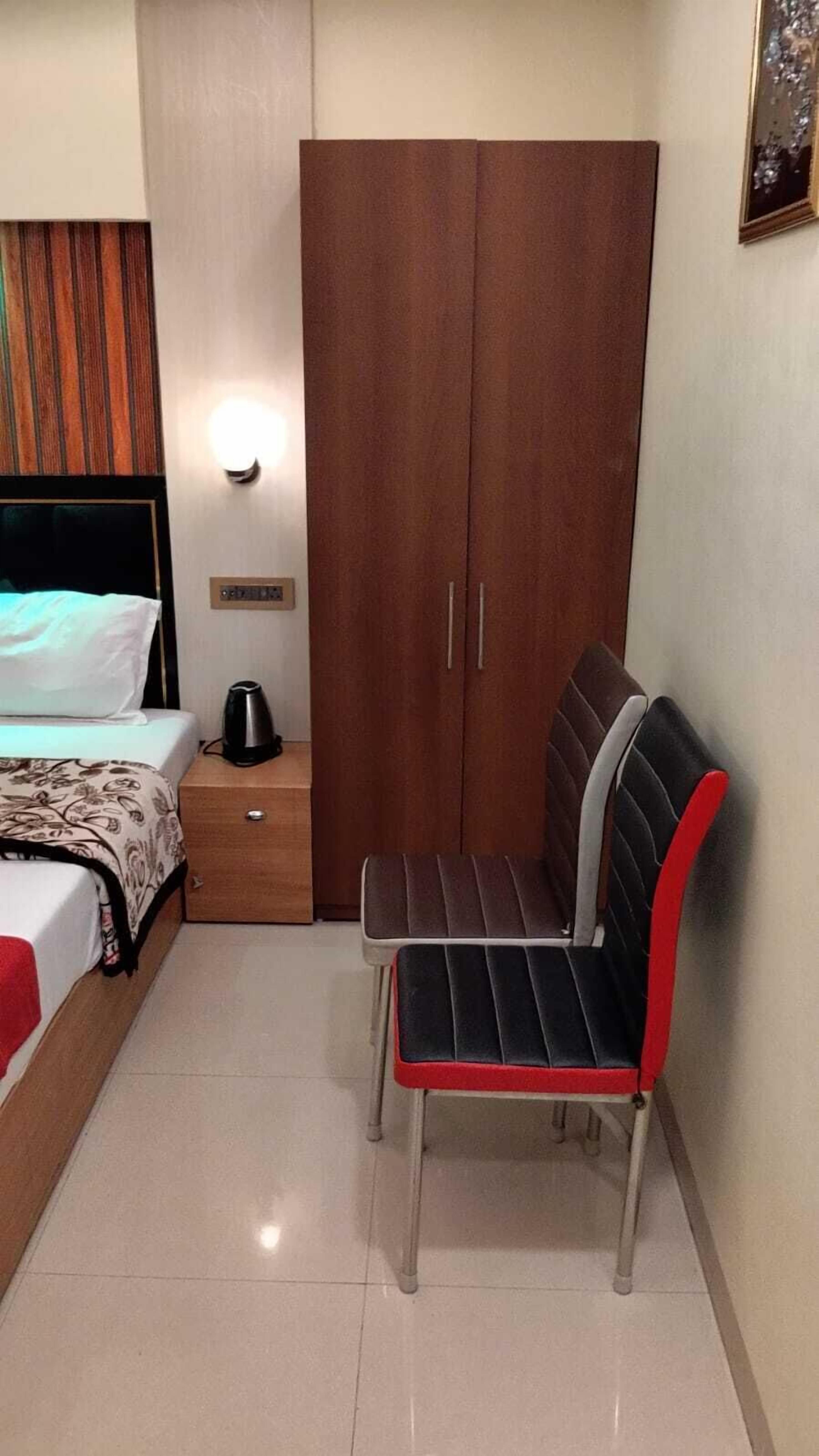 A bedroom with a bed, a nightstand, a wardrobe, and a chair.