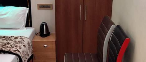 A bedroom with a bed, a nightstand, a wardrobe, and a chair.