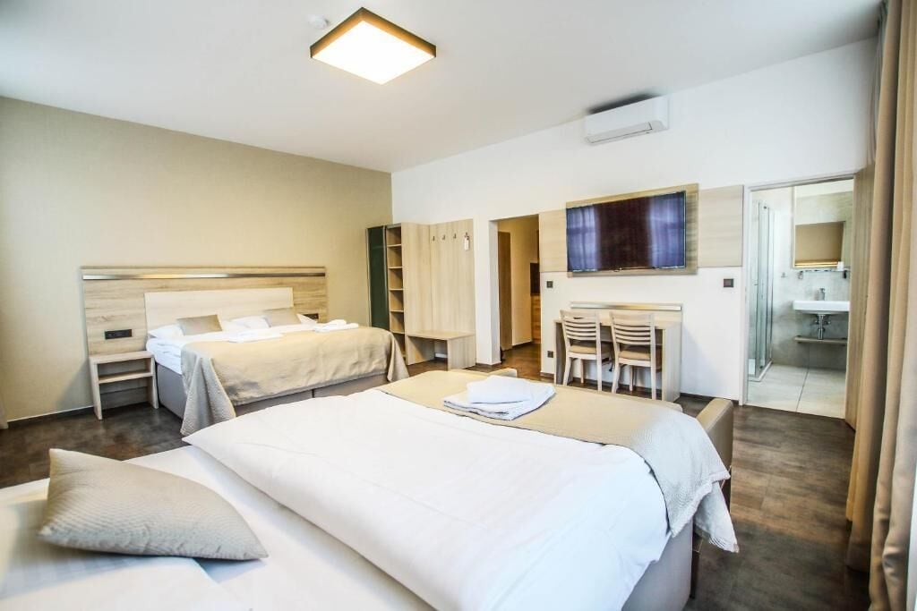 A hotel room with two beds, a desk, a chair, and a bathroom visible through an open door.