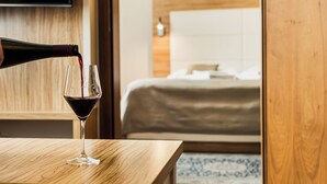 A hotel room with a wooden headboard, a bed with white bedding, and a television mounted on the wall. - Hotel Mariel Znojmo (Znojmo)