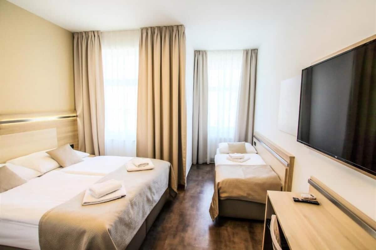 Una habitación de hotel con dos camas, televisión y escritorio.