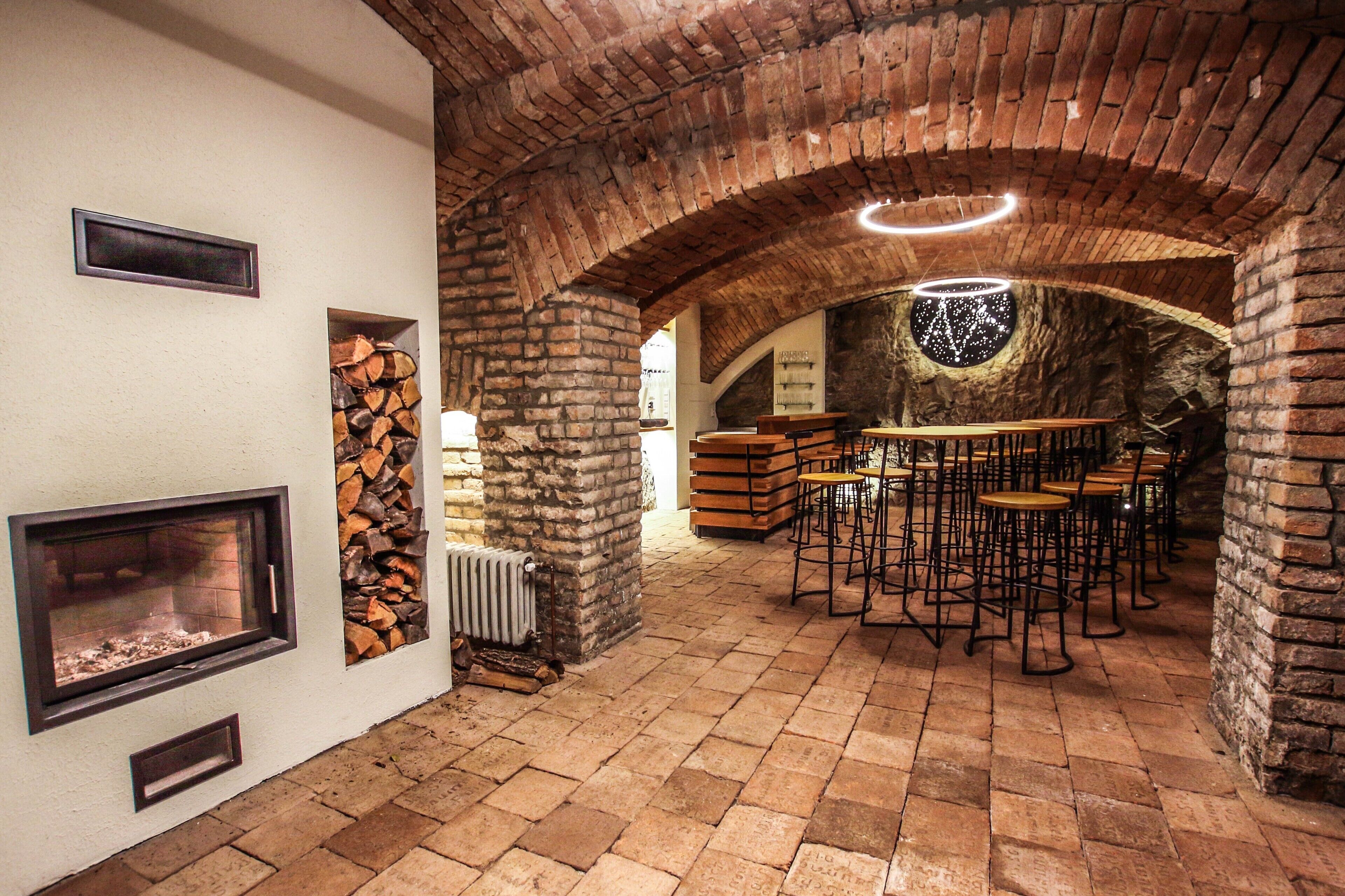 Un interior rústico con arcos de ladrillo, una chimenea y una zona de bar con taburetes.