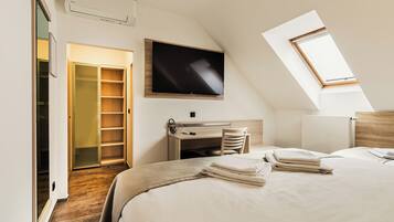 Une chambre à coucher avec un lit, un bureau, une télévision et une fenêtre de toit.