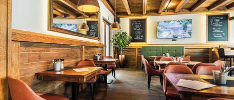A restaurant interior with wooden beams, tables, chairs, and a menu board.