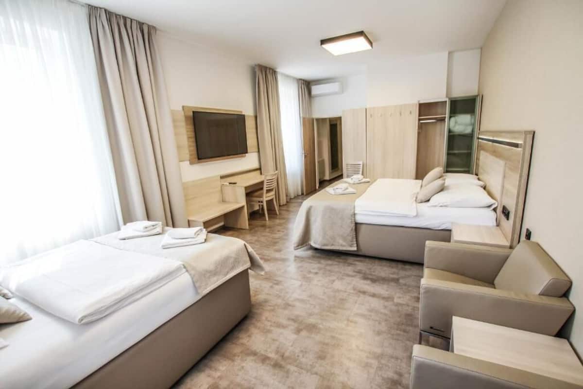 Una habitación de hotel con dos camas, un escritorio, una silla, un televisor y un armario.