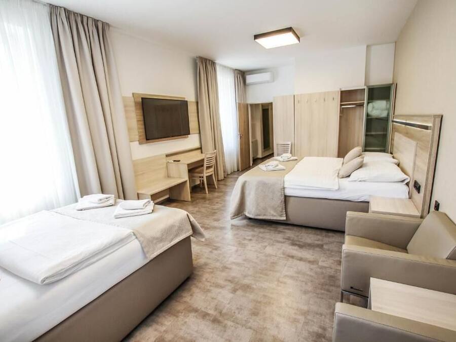 A hotel room with two beds, a desk, a chair, a TV, and a wardrobe.