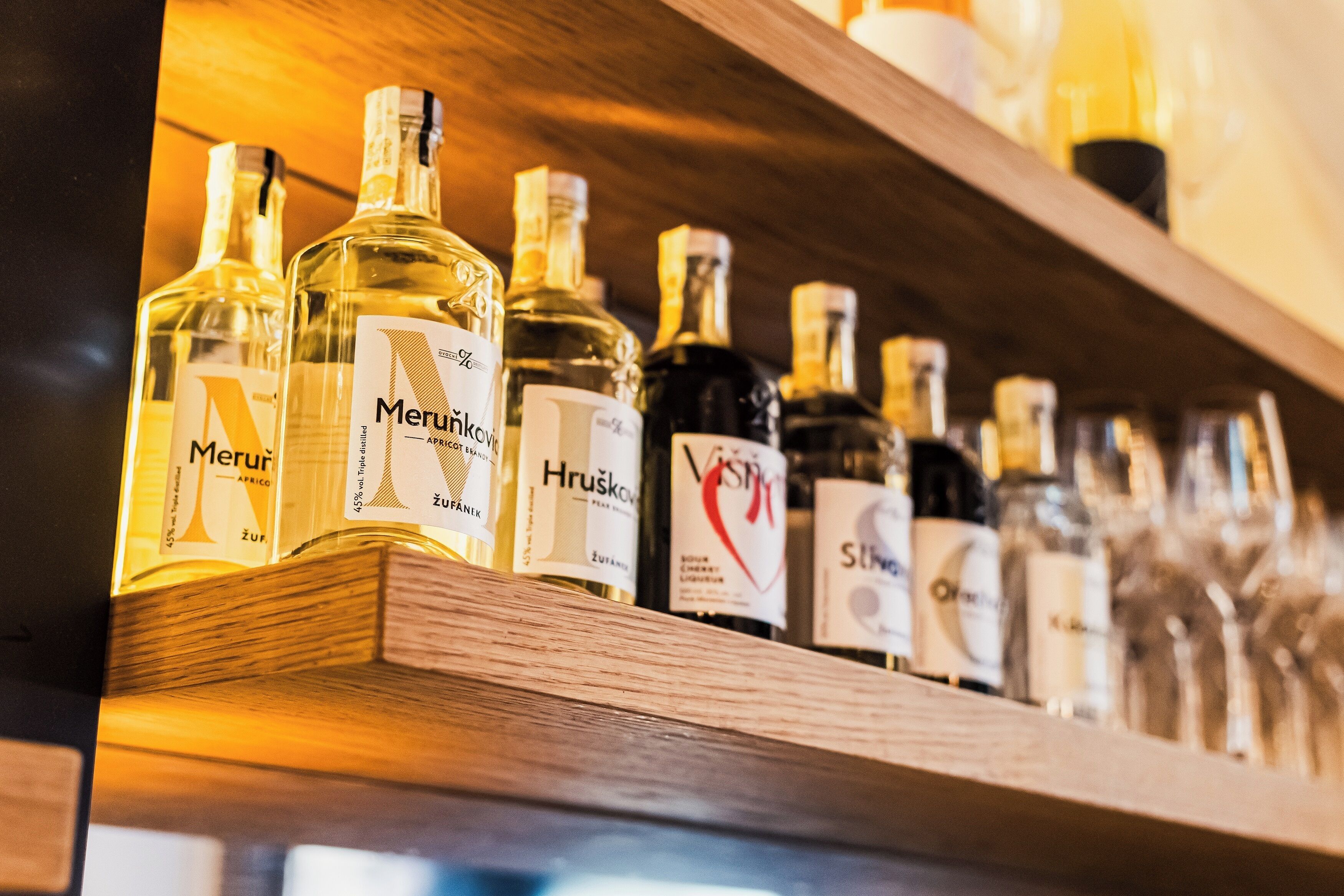 Estante com várias garrafas de álcool, incluindo as marcas Meruńková e Hrušková.