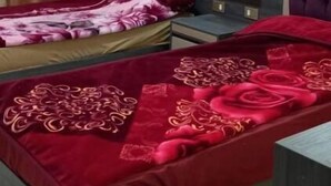 Een slaapkamer met twee bedden, elk voorzien van een rode sprei en een decoratief kussen. Daarboven hangt een grote spiegel en ernaast staat een klein tafeltje.