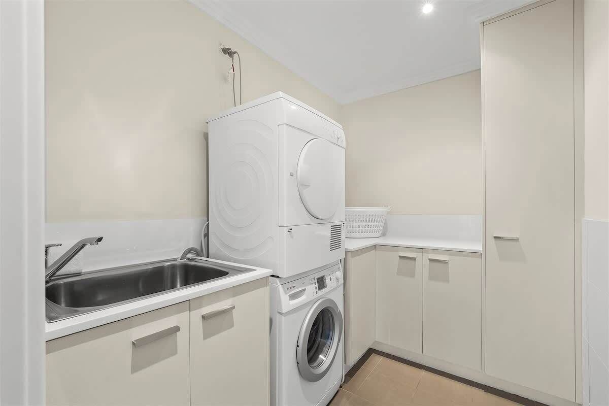 A laundry room with a washing machine, dryer, and sink.
