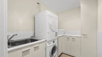 A laundry room with a washing machine, dryer, and sink.