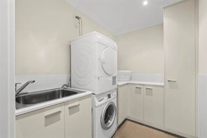 Une buanderie équipée d’un lave-linge, d’un sèche-linge et d’un évier.
