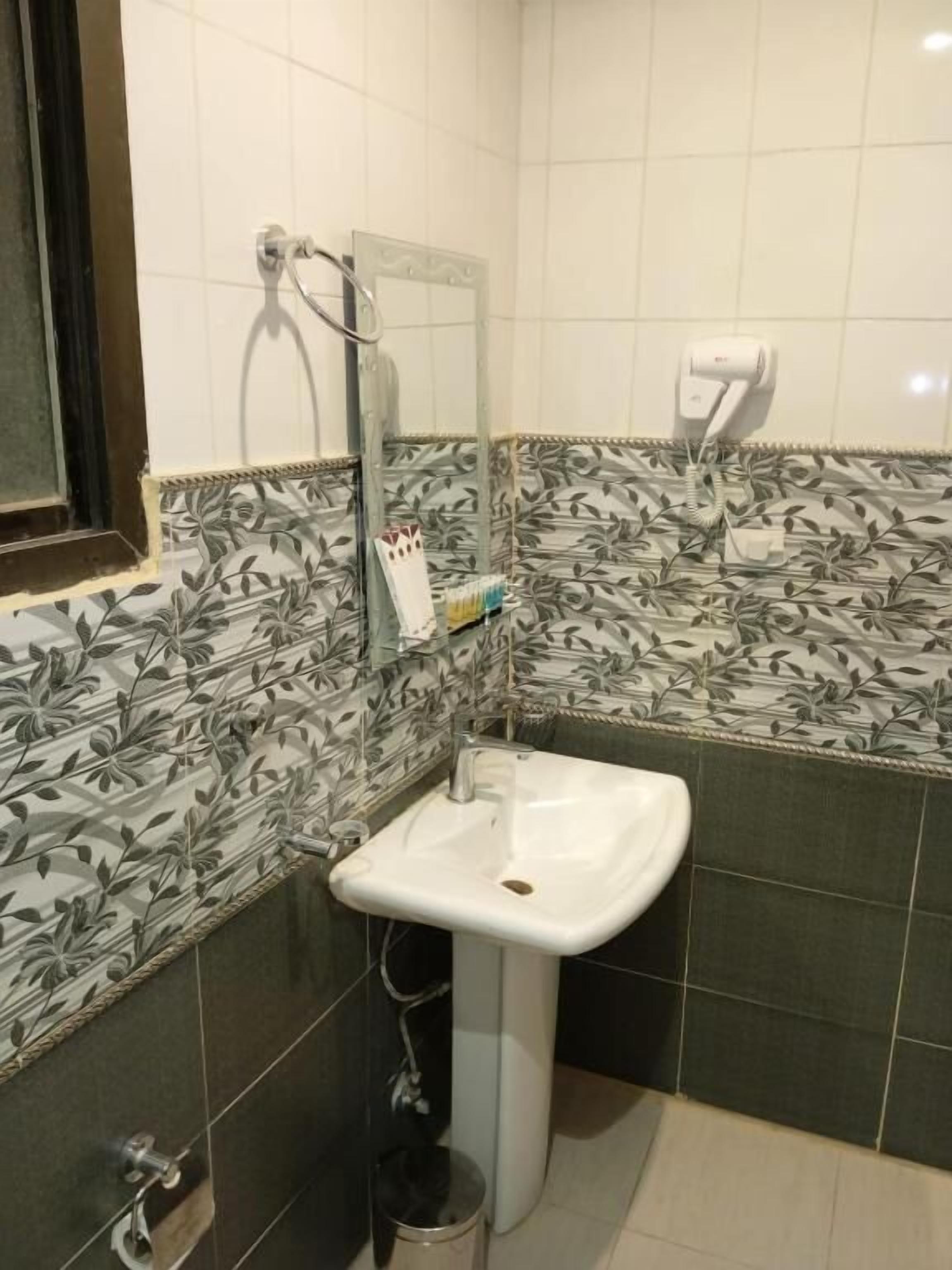 A bathroom with a white sink, a mirror, a towel rack, and a hand dryer.