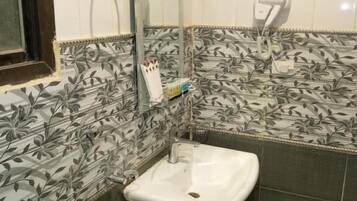 Casa de banho com lavatório branco, espelho, porta-toalhas e secador de mãos.