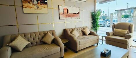 A modern hotel lobby with a sofa set, a coffee table, and artwork on the walls.