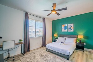 A hotel room with a bed, desk, chair, and a ceiling fan. - Walk To Westgate, Pool, Gym, WD & Free Parking (Glendale)