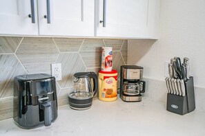 A kitchen counter with a coffee maker, a kettle, a coffee mug, and a knife block. - Walk To Westgate, Pool, Gym, WD & Free Parking (Glendale)