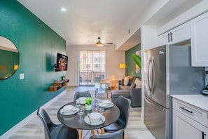 Una cocina moderna con refrigerador, armarios y un comedor con una mesa para dos.