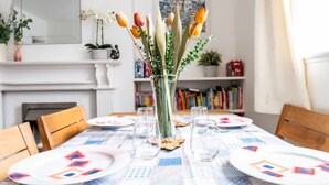 Una mesa de comedor dispuesta con platos, vasos y un jarrón con flores.