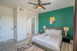 A hotel room with a bed, two bedside tables with lamps, a ceiling fan, and a green accent wall. - Lavish 2BD| Walk to Westgate+Pool+Gym+W/D (Glendale)