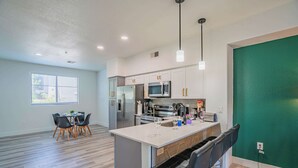 A modern kitchen with white cabinets, stainless steel appliances, and a central island with bar stools. - Chic Modern Stay, Pool, W/D, Gym, Walk to Westgate (Glendale)