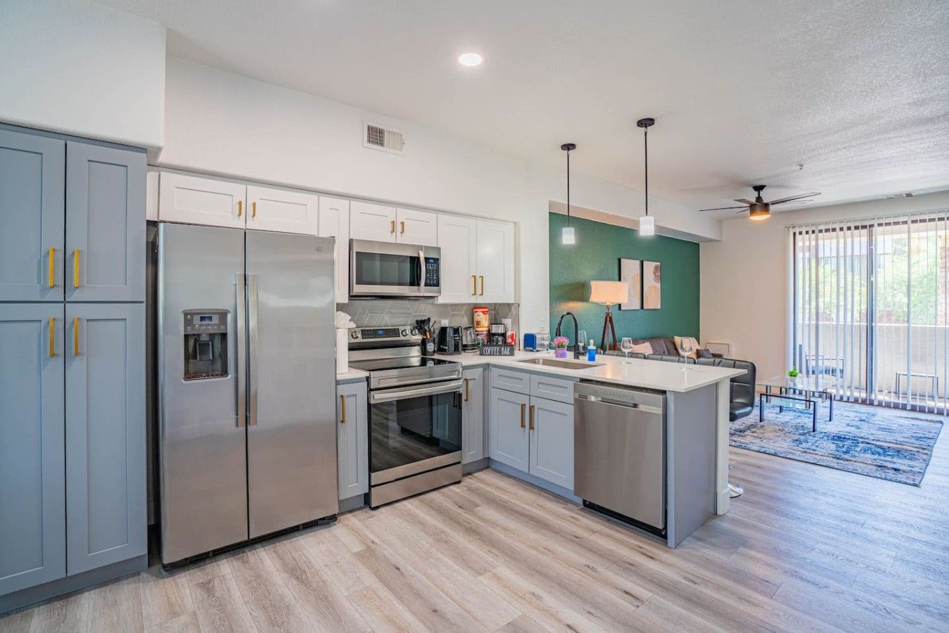 A modern kitchen with stainless steel appliances, a coffee bar, and a dining area with a view.
