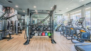A gym with weightlifting equipment, treadmills, and a wall with fitness posters. - Chic Modern Stay, Pool, W/D, Gym, Walk to Westgate (Glendale)