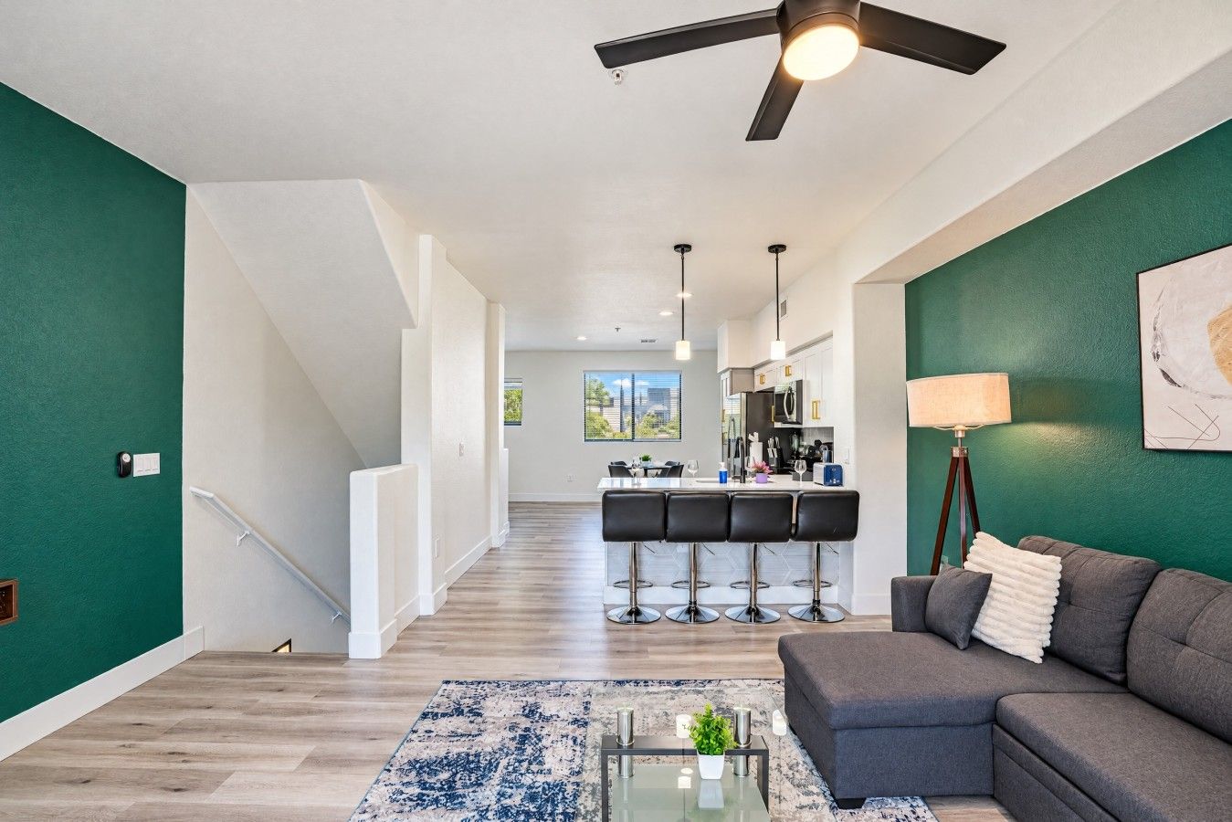 A modern living room with a sofa, a coffee table, and a bar area with stools.