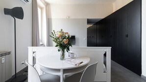 A modern kitchen with a white dining table, chairs, a vase with flowers, and a coffee mug. - Italianway Easy - Giambellino 67 A (Milano)
