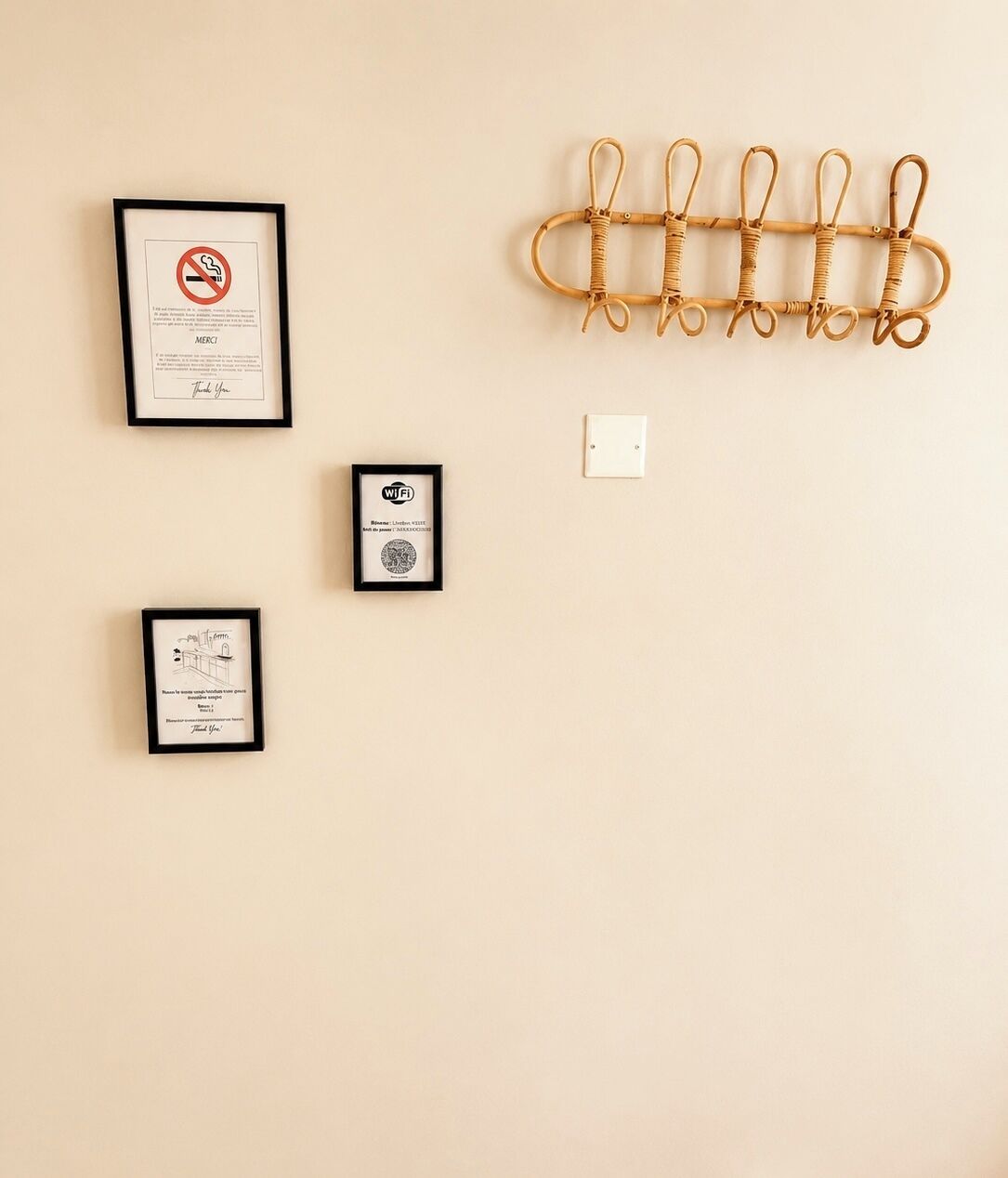 A wall with four framed items: a no-smoking sign, a framed certificate, a framed certificate with a logo, and a wall-mounted hook.