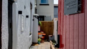 A narrow alleyway with a red gate and a sign for Towpath Cottage on 98 Tarvin Road.