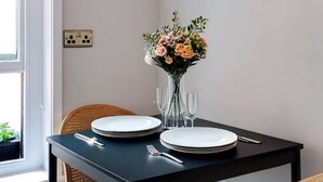 A dining table set with plates, cutlery, and a vase of flowers.