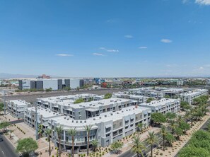 A modern multi-story building complex with a central courtyard, surrounded by palm trees and a clear sky.