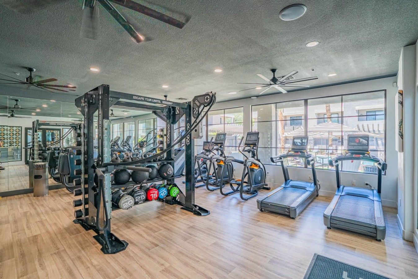 Un gimnasio con equipo de ejercicio, cintas de correr y zonas de levantamiento de pesas.