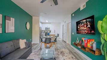 A living room with a sofa, coffee table, and a TV mounted on the wall.