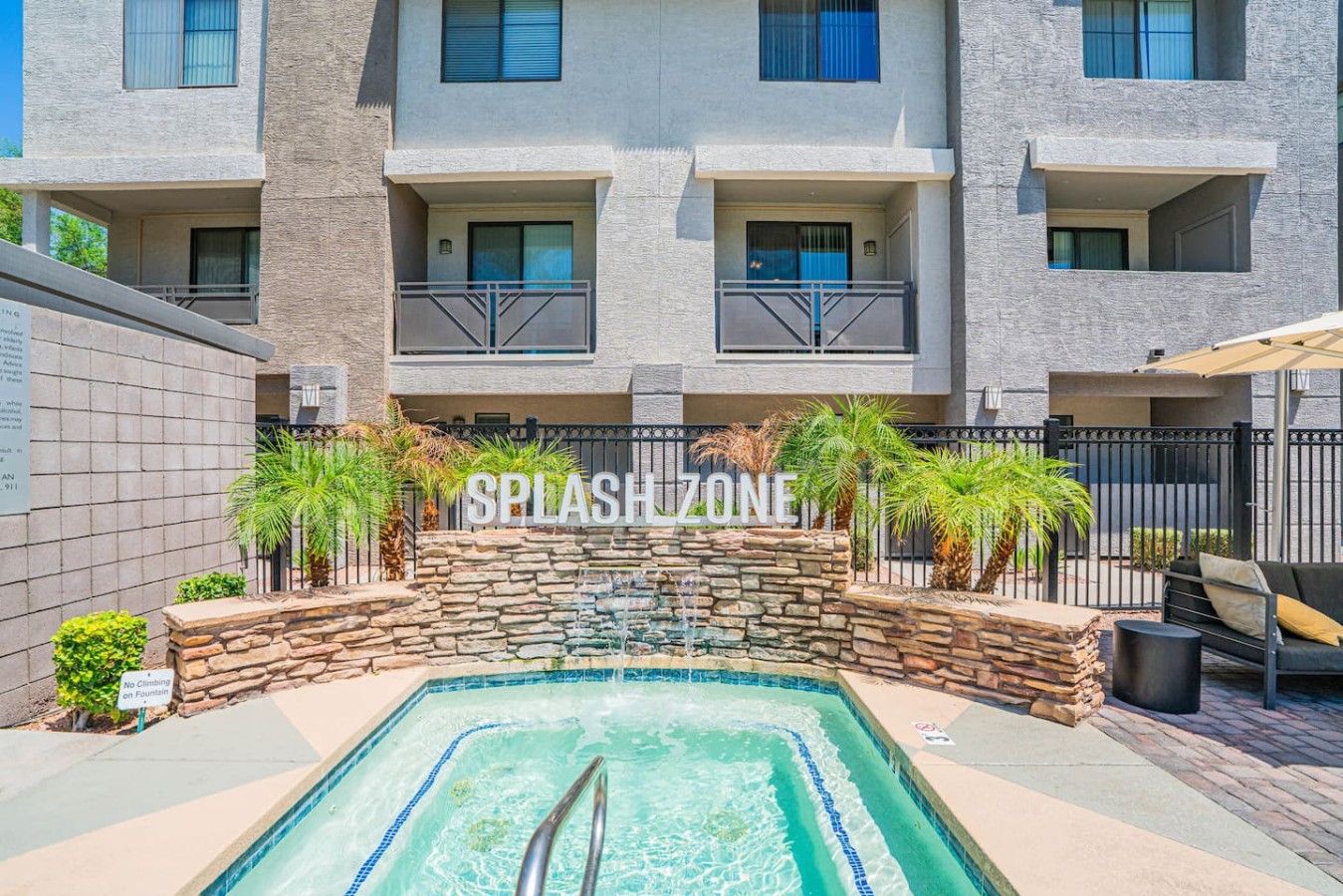 A swimming pool with a stone wall and a sign that reads 'SPLASHZONE'.