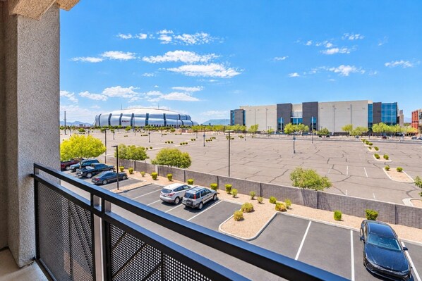 A parking lot with several cars, a large building with a curved roof, and a clear blue sky.