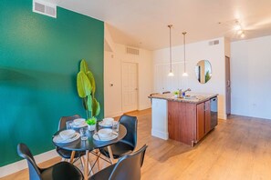 A compact living space with a dining area, kitchenette, and a green accent wall. - Clean Westgate | Pool, Gym W/D Hot Tub Parking (Glendale)