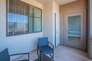 A balcony with a chair, a door, and a window with blinds. - Clean Westgate | Pool, Gym W/D Hot Tub Parking (Glendale)