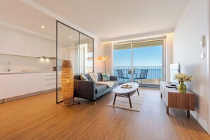 A modern living room with a sofa, a coffee table, a side table with a vase, and a view of the balcony. - Atlantic Nest by Holiday Rental Madeira (Câmara de Lobos)
