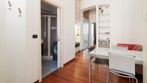 Un interior moderno con zona de comedor, lavadora y cabina de ducha de vidrio.