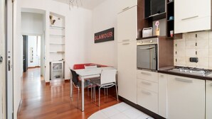 Una cocina moderna con armarios blancos, un horno de acero inoxidable y un comedor con mesa y sillas blancas.
