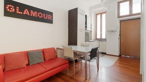 Un espacio habitable moderno con un sofá rojo, una mesa de comedor y una zona de cocina.
