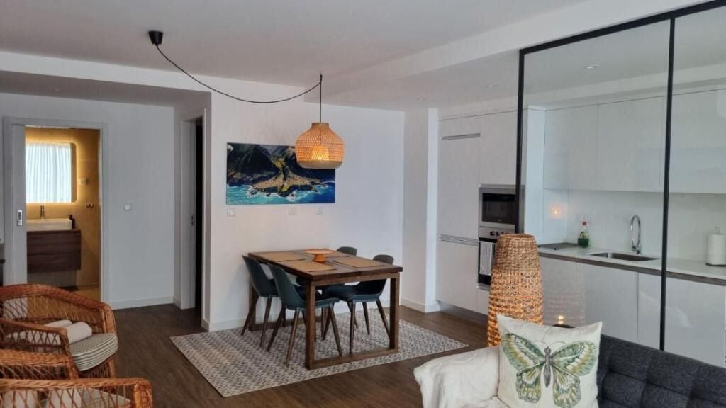A modern living room with a dining area, a kitchen, and a bathroom.