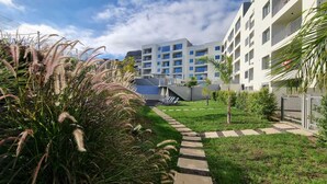 A modern apartment complex with a central courtyard, a pathway, and surrounding greenery.