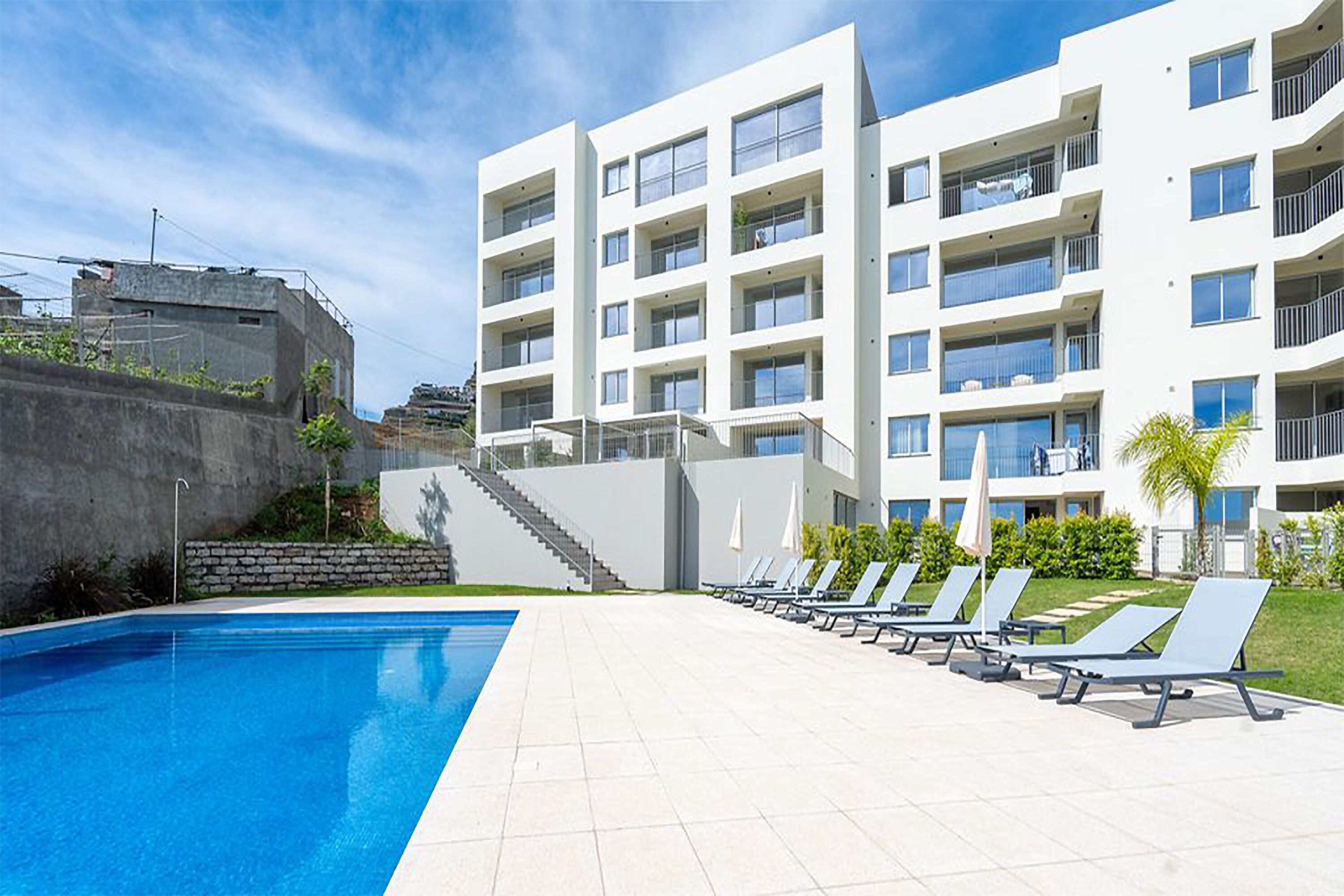 Ein modernes Gebäude mit Schwimmbad und Liegestühlen.