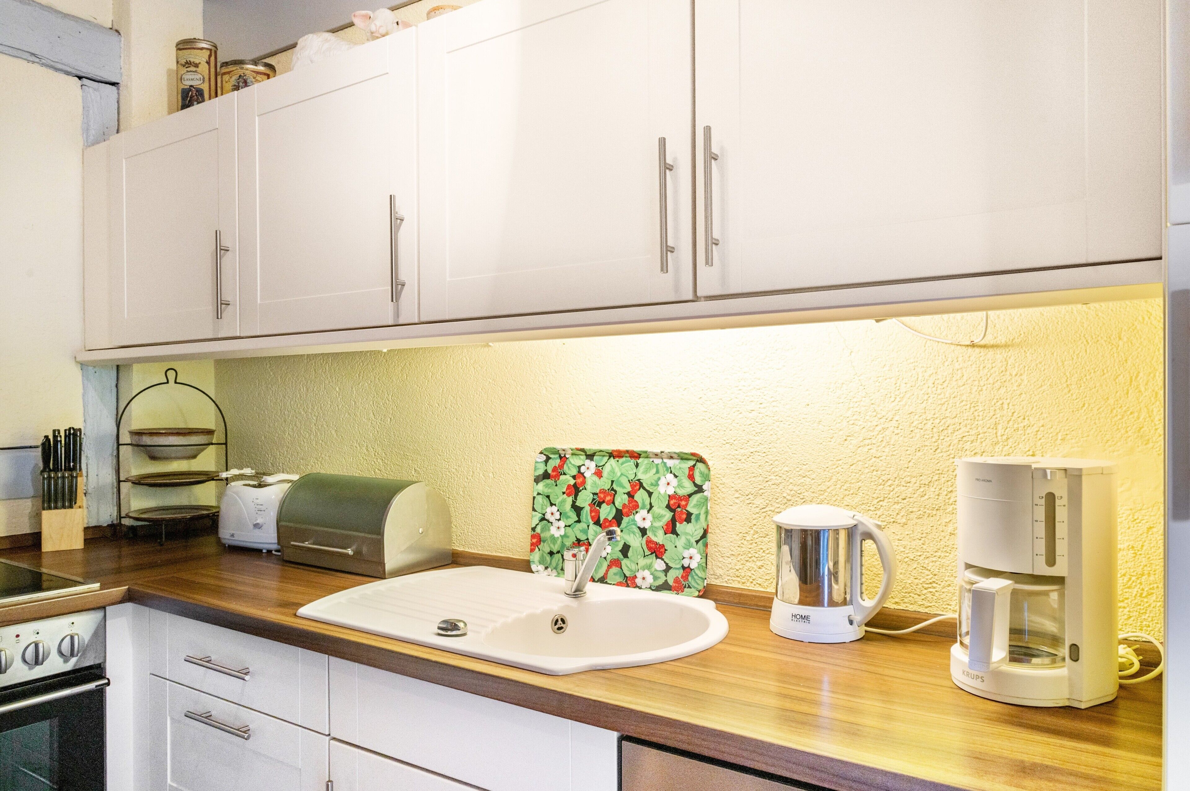 Una cucina con mobili bianchi, un tostapane, un bollitore e una macchina per il caffè.
