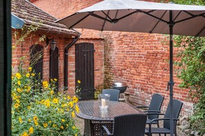 A patio with a table and chairs, a grill, and a brick wall. - Holiday Home 'Altes Nachtwächterhaus' with Courtyard and Wi-Fi (Rühstädt/OT Abbendorf)